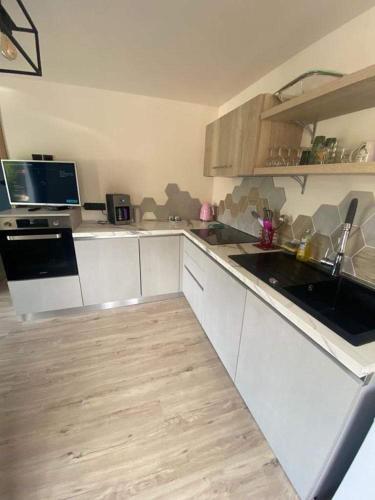 une cuisine avec des armoires blanches et un plancher en bois dans l'établissement Maison cosy au calme, à La Colle-sur-Loup