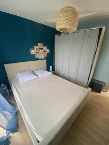 ein weißes Bett in einem Zimmer mit blauer Wand in der Unterkunft Maison cosy au calme in La Colle-sur-Loup