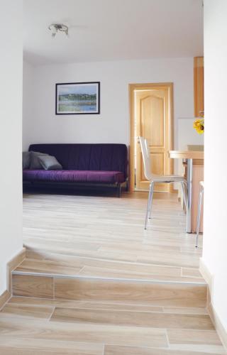 a living room with a purple couch and a table at APARTMA KMETIJA ROVAN in Vrhpolje