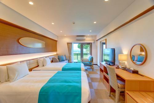 a hotel room with two beds and a desk at Ishigaki Seaside Hotel in Ishigaki Island