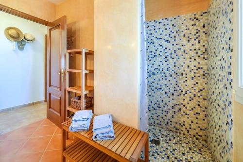 Łazienka z prysznicem i niebieskimi ręcznikami na ławce w obiekcie Villa Turo del Sol w mieście Cala Murada