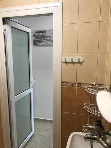 a bathroom with a glass shower door and a sink at Familienapartment am Strand in Primorsko in Primorsko