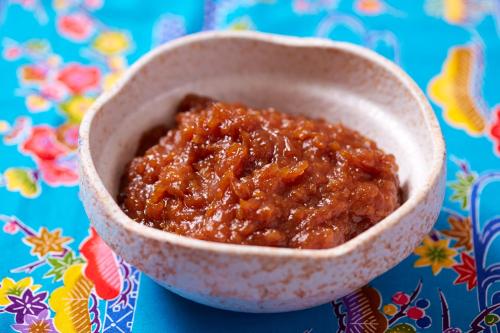 a bowl of chili sauce sitting on a table at Sun Palace Kyuyokan in Naha
