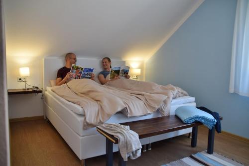 a man and woman sitting under a bed reading books at Ferienwohnung auf dem Dorf, Külsheim in Külsheim
