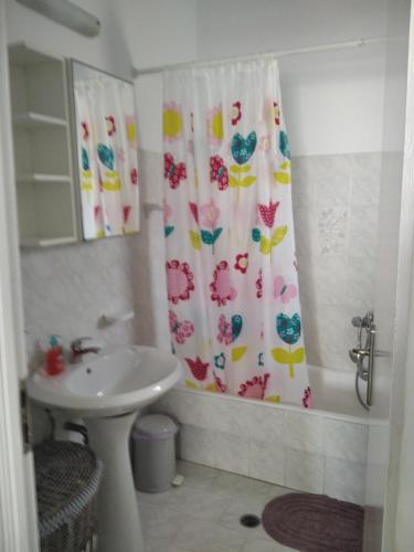 a bathroom with a shower curtain and a sink at Myconian Cottage in Ano Mera
