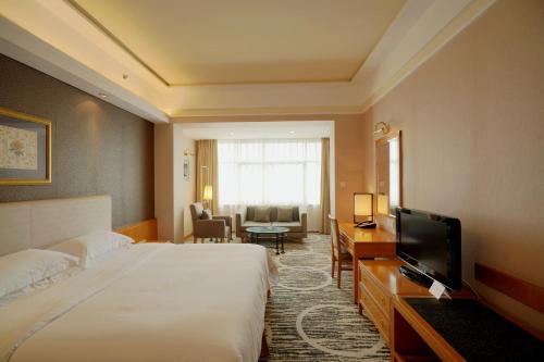 
a hotel room with a large bed and a television at Guangzhou Baiyun Hotel in Guangzhou
