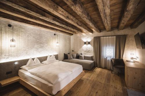 um quarto com uma grande cama branca e um sofá em Autentis em Rasùn di Sotto