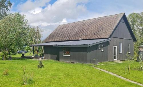 a green house with a gray roof on a yard at Šķūnis - vieta mieram un atpūtai in Mazlauki