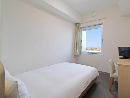 a bedroom with a white bed and a window at CHISUN BUDGET Kanazawa Ekimae in Kanazawa