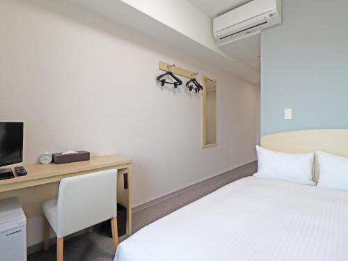 a room with a bed and a desk with a computer at CHISUN BUDGET Kanazawa Ekimae in Kanazawa