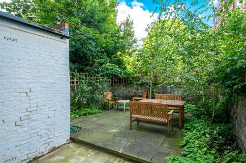 a patio with a wooden table and benches at Stylish flat with garden in Notting Hill in London