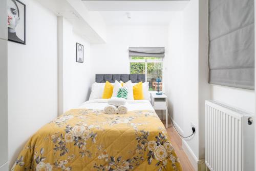 a bedroom with a large bed with a yellow blanket at Stylish flat with garden in Notting Hill in London