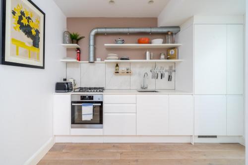 a kitchen with white cabinets and a sink at Stylish flat with garden in Notting Hill in London