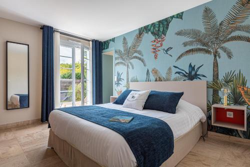 a bedroom with a large bed with a mural of palm trees at Une Escale à Pornic chambres d'hôtes 4 épis in Pornic