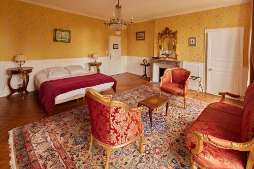 - une chambre avec un lit, des chaises et une cheminée dans l'établissement Logis Hôtel & Restaurant Chateau de la Marjolaine, à Essômes-sur-Marne