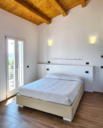 a white bedroom with a bed and a window at VillAlba Affittacamere in Camerano