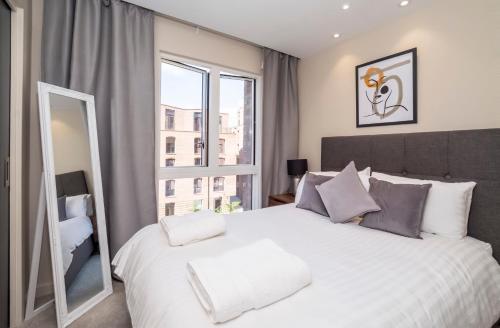 una camera da letto con un grande letto bianco e una grande finestra di City Apartments - Hudson Quarter a York