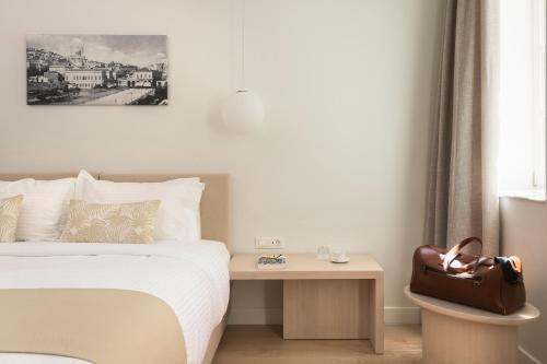 a bedroom with a bed and a table with a purse at SYROS SOUL LUXURY SUITES in Ermoupoli