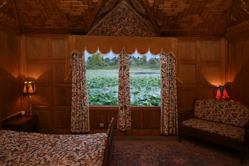 a bedroom with a window with a bed and a chair at Kings Houseboats in Srinagar