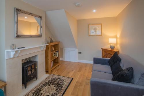 a living room with a blue couch and a fireplace at Sage Cottage in Atworth