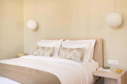 a bedroom with a bed with white sheets and pillows at SYROS SOUL LUXURY SUITES in Ermoupoli