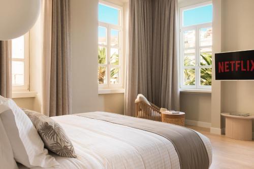a bedroom with a bed and two windows at SYROS SOUL LUXURY SUITES in Ermoupoli