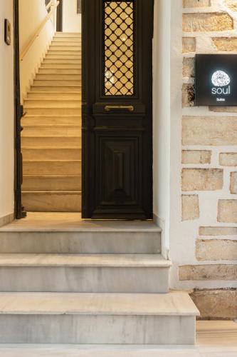 a black door on a house with stairs at SYROS SOUL LUXURY SUITES in Ermoupoli