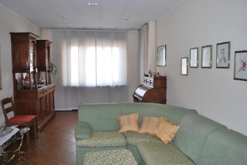 - un salon avec un canapé vert et un piano dans l'établissement Tra Langhe, Roero e Monferrato. San Damiano d'Asti, à San Damiano dʼAsti