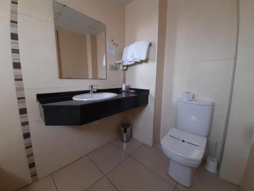 a bathroom with a sink and a toilet and a mirror at Hotel Avenida El Morell in El Morell