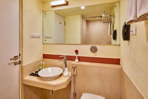 a bathroom with a sink and a mirror at Coraltree Hotel Bangalore in Bangalore