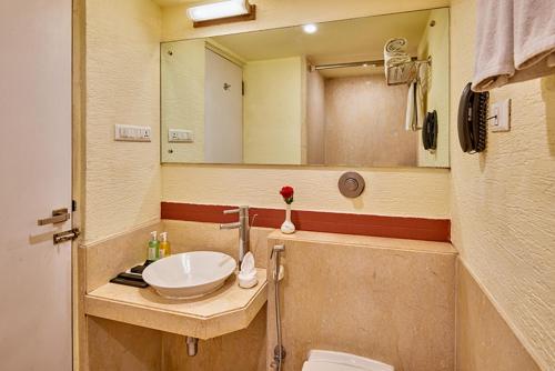 a bathroom with a sink and a mirror at Coraltree By Goldfinch Hotels Bangalore in Bangalore