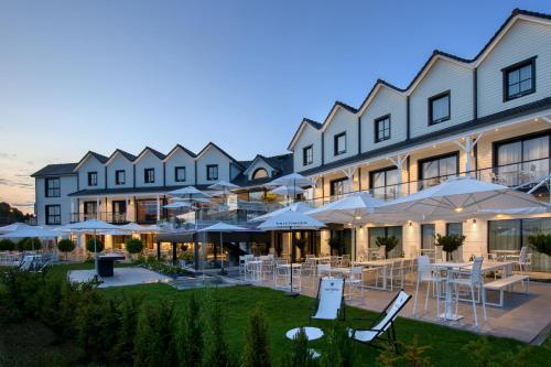 a hotel with tables and umbrellas in front of it at Best Western Plus Le Fairway Hotel & Spa Golf d'Arras in Anzin-Saint-Aubin