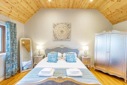 a bedroom with a large bed with blue pillows at Thistle Lodge 20 with Hot Tub in Belladrum