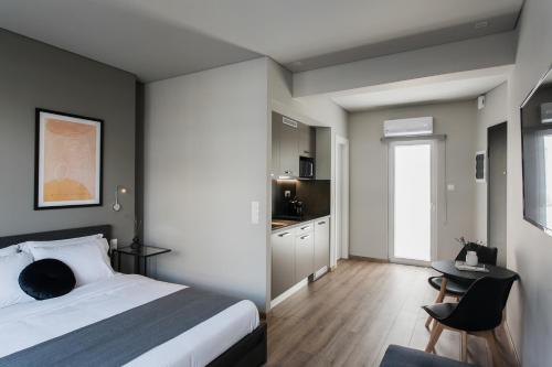 アテネにあるWYZ Athens Apartments by UPSTREETのベッドとテーブルとキッチンのある寝室