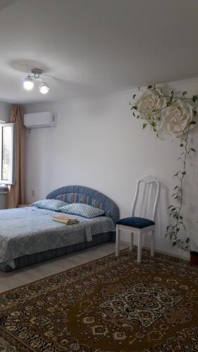 1 dormitorio con 1 cama y 1 silla en Светлая квартира для гостей, en Kyzylorda