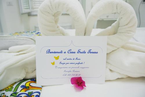 een bordje op een bed met een handdoekendier bij Apartment Casa Suite Teresa , centro di Forio , Ischia in Ischia