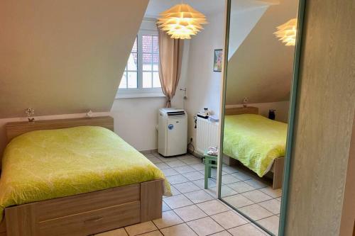 ein kleines Schlafzimmer mit 2 Betten und einem Spiegel in der Unterkunft Le papillon,Logement cosy en Alsace in Erstein