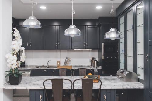 a kitchen with black cabinets and a counter with chairs at Casa da Ni - Douro in Arcos