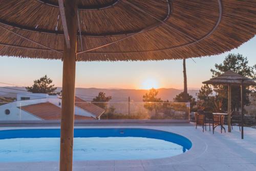 a pool with a straw umbrella and a table and chairs at Casa da Ni - Douro in Arcos