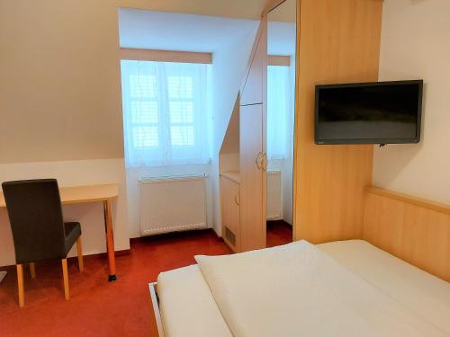a room with a bed and a desk and a tv at Gästehaus Ferk - Frühstückspension, Bed & Breakfast in Bad Radkersburg