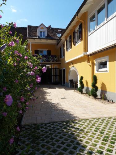 a yellow house with a brick driveway and flowers at Gästehaus Ferk - Frühstückspension, Bed & Breakfast in Bad Radkersburg