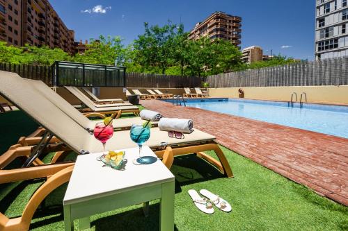 - une piscine avec des chaises longues et une table avec des boissons dans l'établissement Hotel Valencia Oceanic Affiliated by Meliá, à Valence