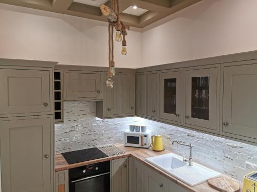 uma cozinha com armários brancos, um lavatório e um micro-ondas em Seashell luxury apartment em Burnham-on-Sea