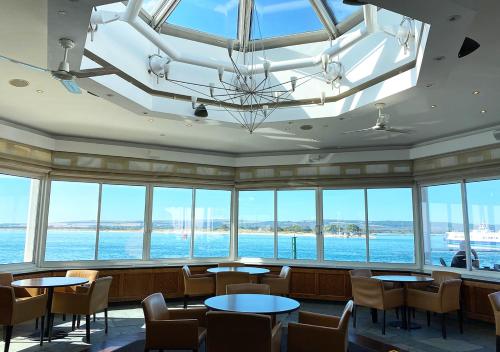 a restaurant with tables and chairs and large windows at Haven Hotel in Poole