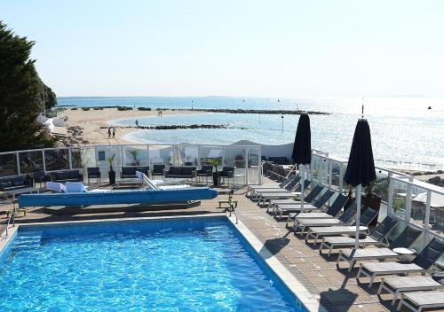 a swimming pool with chairs and umbrellas next to a beach at Haven Hotel in Poole