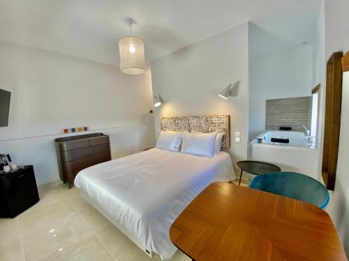 a bedroom with a bed and a wooden table at La Maison des Vendangeurs - TABLE D'HÔTES le soir du jeudi au dimanche- Jacuzzi - Balnéo SPA - ACCES PISCINE pour toutes les chambres sauf STUDIO COQUET- Piscine de mai à mi-octobre in Martignargues