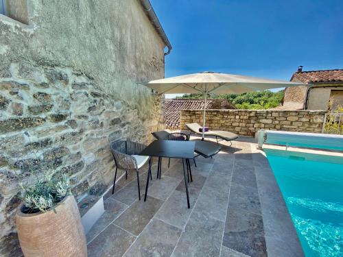 a patio with a table and an umbrella and a swimming pool at La Maison des Vendangeurs - TABLE D'HÔTES le soir du jeudi au dimanche- Jacuzzi - Balnéo SPA - ACCES PISCINE pour toutes les chambres sauf STUDIO COQUET- Piscine de mai à mi-octobre in Martignargues