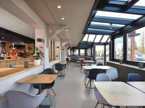 シャルルロワにあるibis Charleroi Airport Brussels Southのテーブルと椅子、窓のあるレストラン