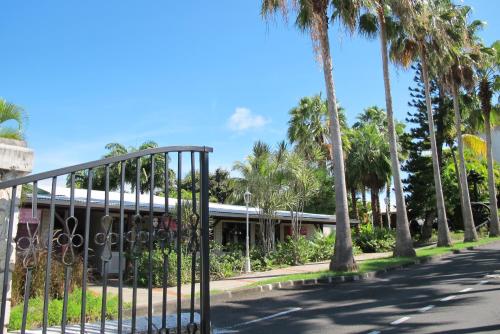 a gate in front of a building with palm trees at Hotel Auberge de la Vieille Tour in Le Gosier