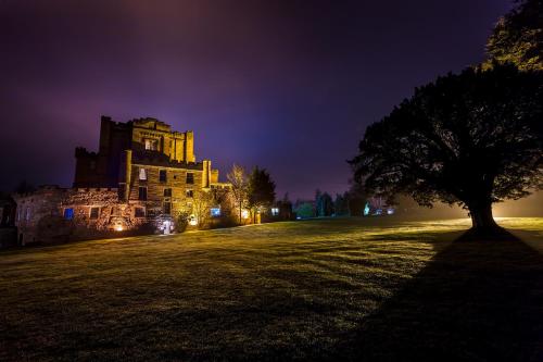a tree in front of a building at night at Dalhousie Castle Hotel in Bonnyrigg